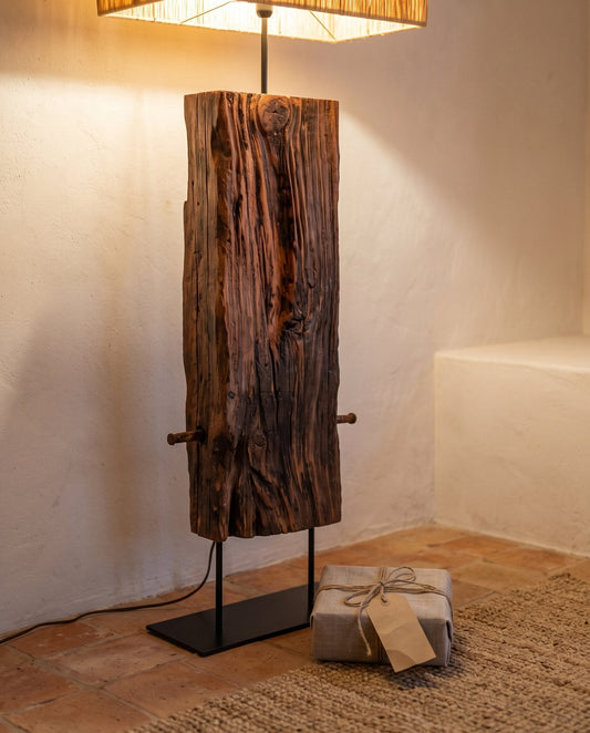 Candeeiro de pé FAROL, em travessa de caminho de ferro recuperada, com cavilha de ferro visível e abajur de ráfia de papel, aceso junto a um embrulho de presente em tecido de linho