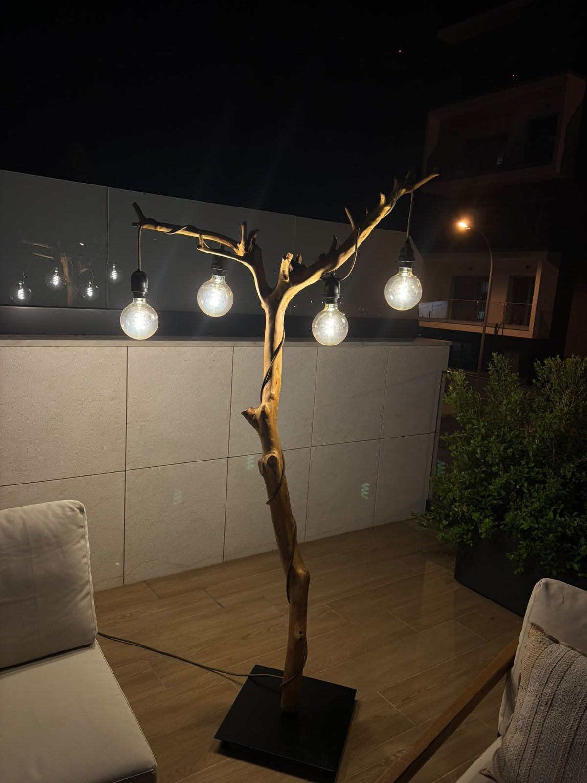 Candeeiro de pé de exterior ALCE em oliveira aceso à noite, com quatro lâmpadas suspensas dos ramos, numa varanda | LAMS Woodcrafts